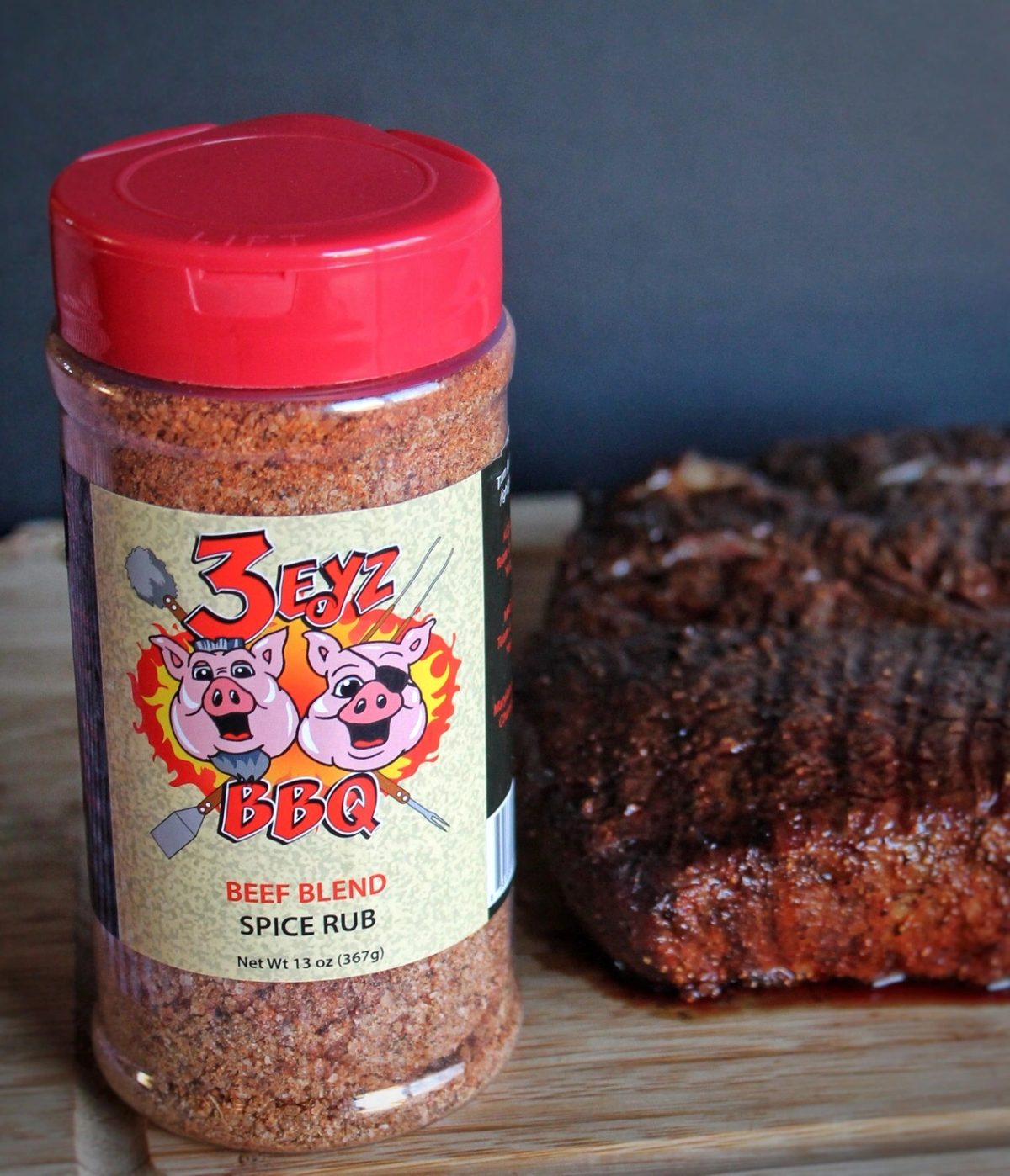 3 Eyz BBQ Beef Blend Spice Rub, 13 oz shaker, next to a seasoned brisket