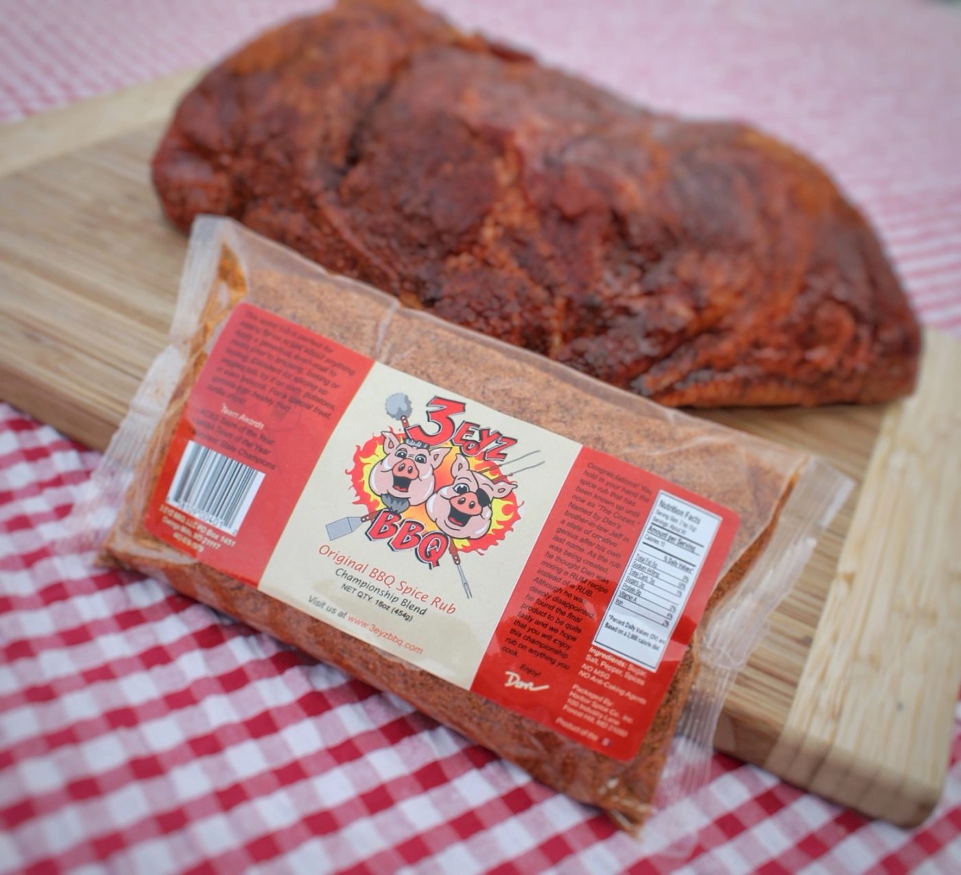 Bag of 3 Eyz Original BBQ Spice Rub next to a seasoned pork butt